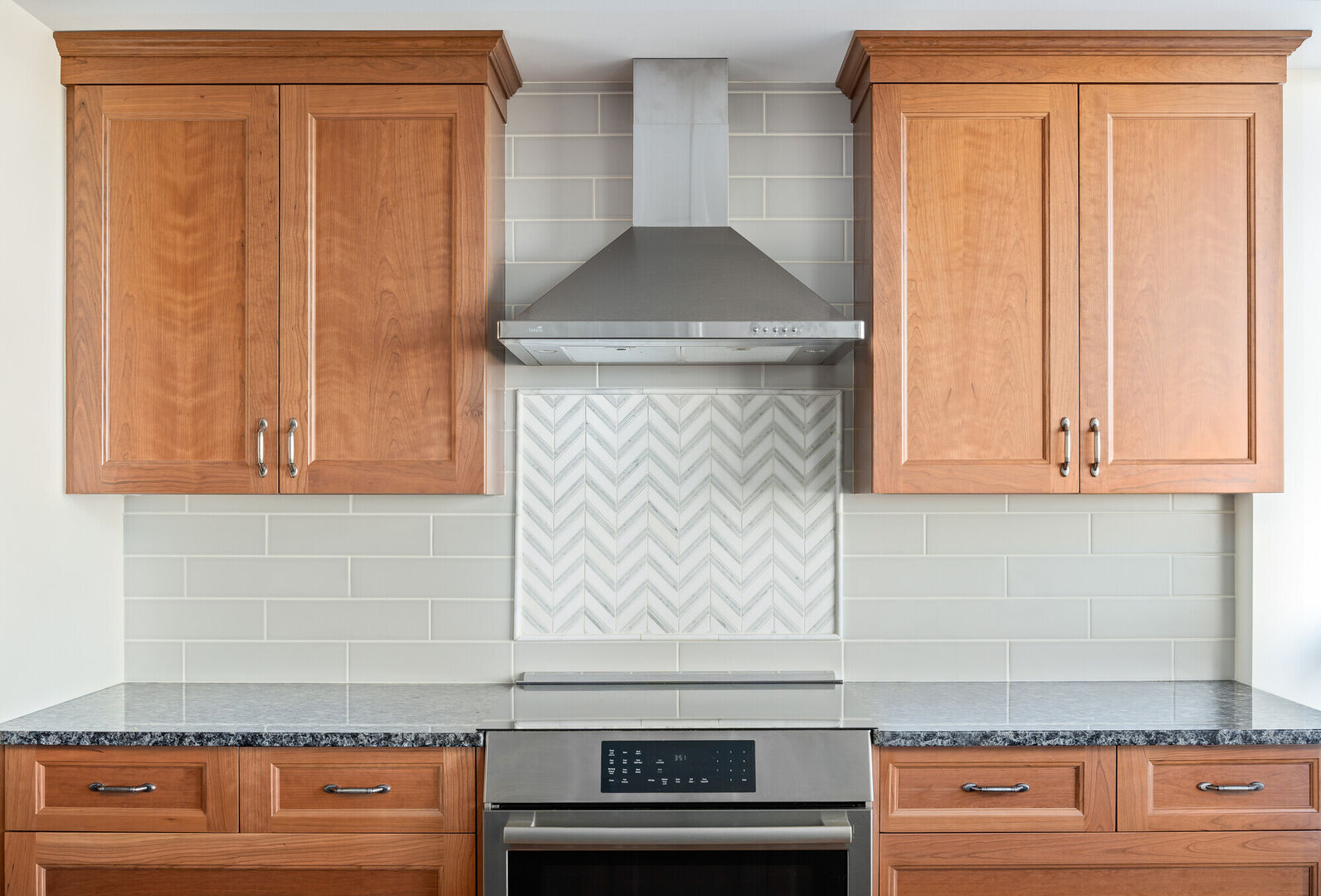 Modern kitchen renovation with subway tile, wood cabinets and chevron tile